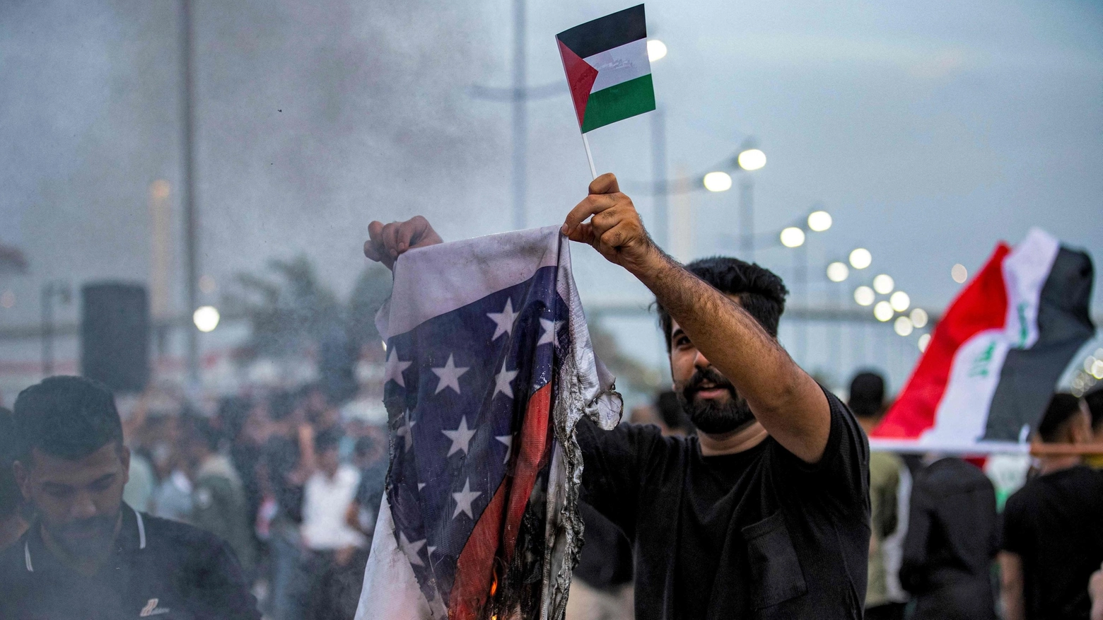 Iraq, una uomo brucia una bandiera americana durante una manifestazione pro-Palestina (Ansa)