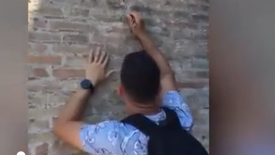 Turista incide il nome dell'amata su un muro del Colosseo, un frame del video diffuso sui social