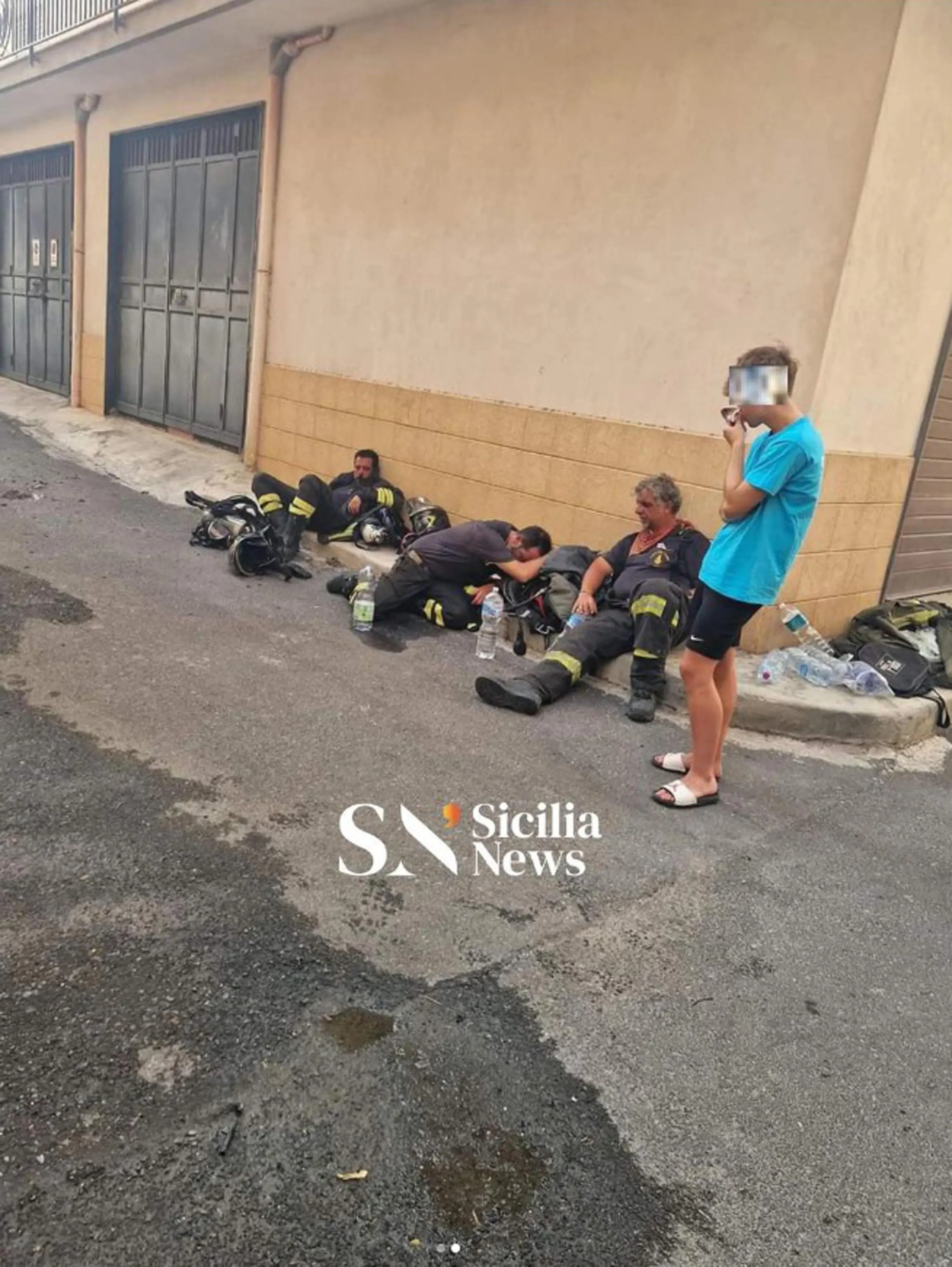 Incendi in Sicilia, la foto simbolo: vigili del fuoco stremati sul  marciapiede