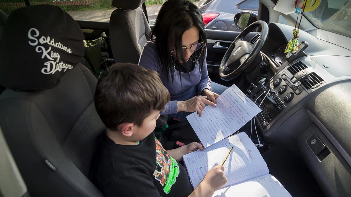 Una mamma che fa fare i compiti al figlio in auto (Dire)