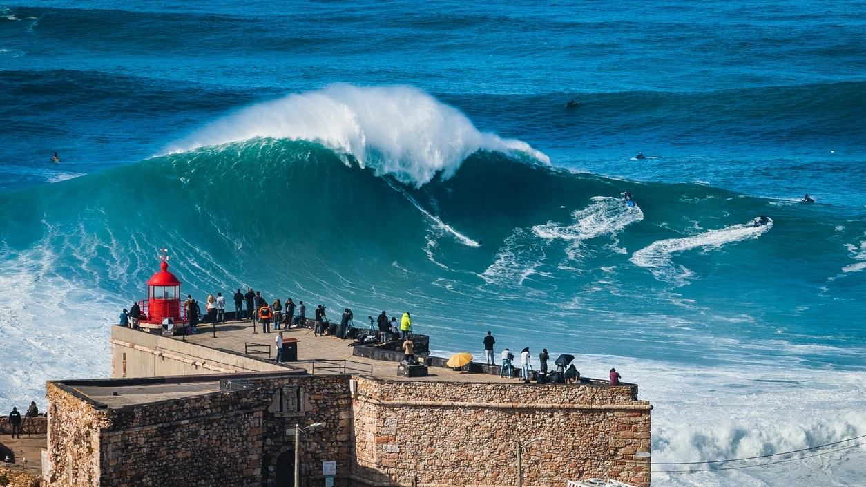 Nazare, Portugal, Surfer Riding Huge Wave Near the Fort of Nazare Lighthouse