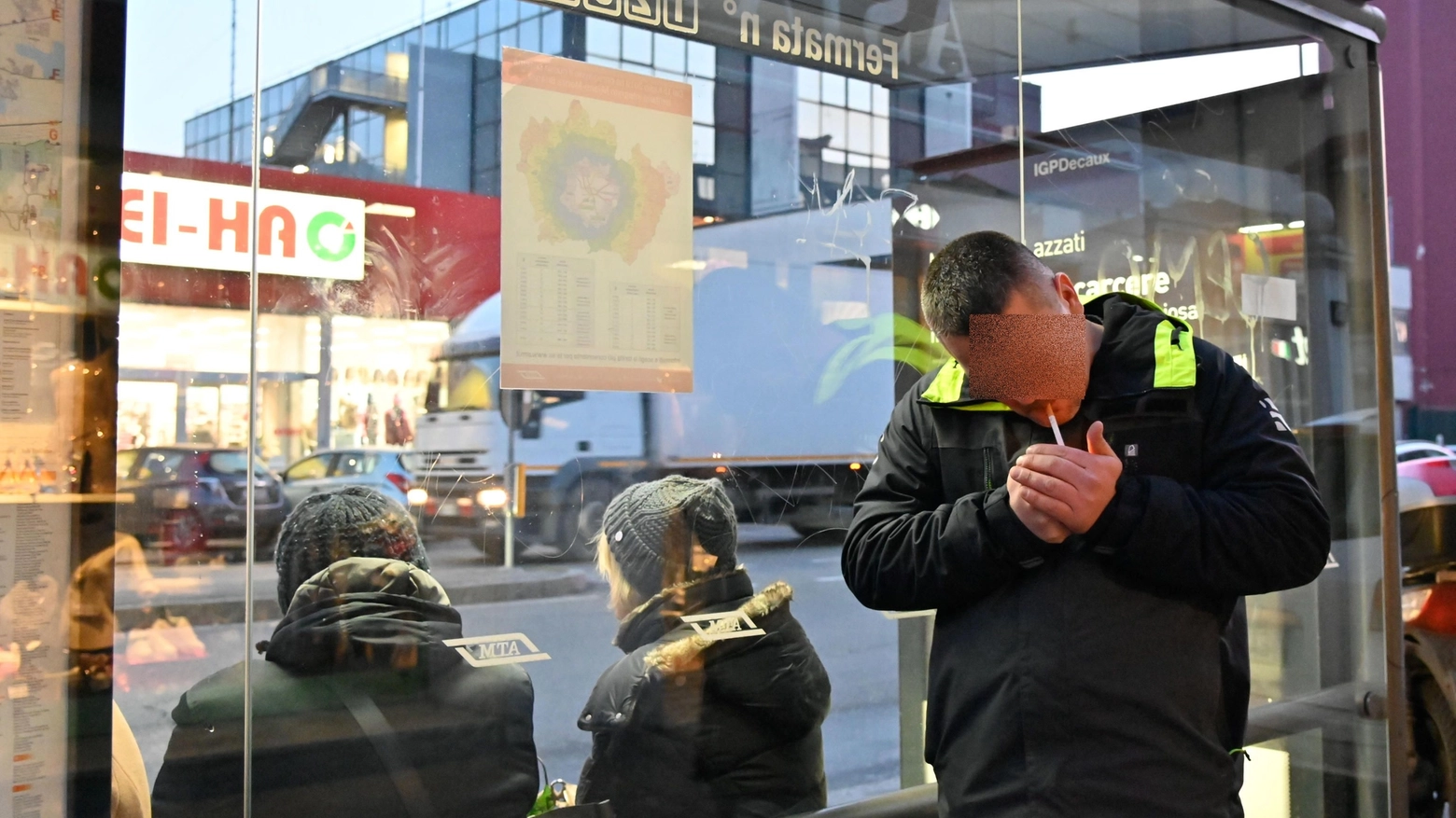 Un fumatore alla fermata dell'autobus a Milano (Ansa)