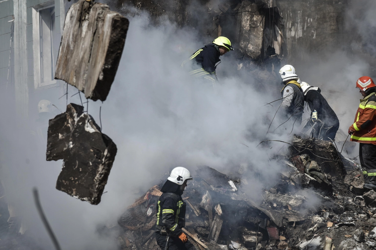 Vigili del fuoco scavano sotto le macerie del palazzo bombardato a Uman (Ansa)