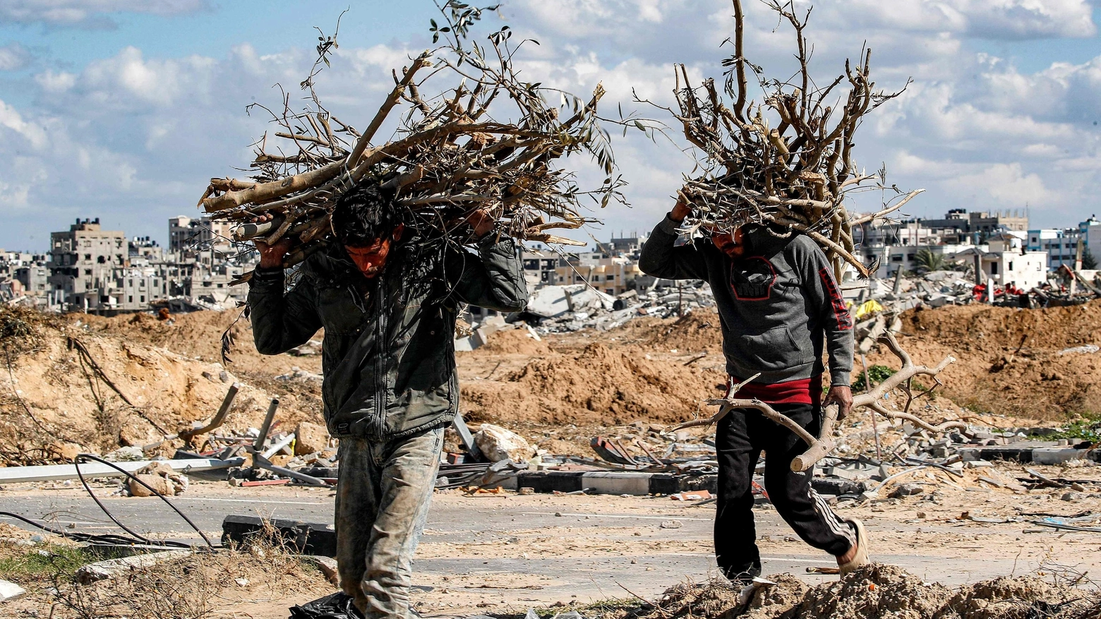 Uomini trasportano legna per accendere il fuoco a Gaza (Ansa)