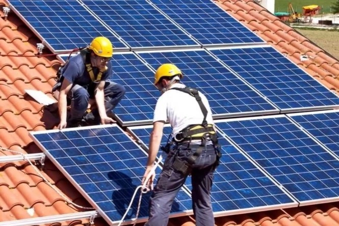 Due tecnici installano una serie di pannelli fotovoltaici