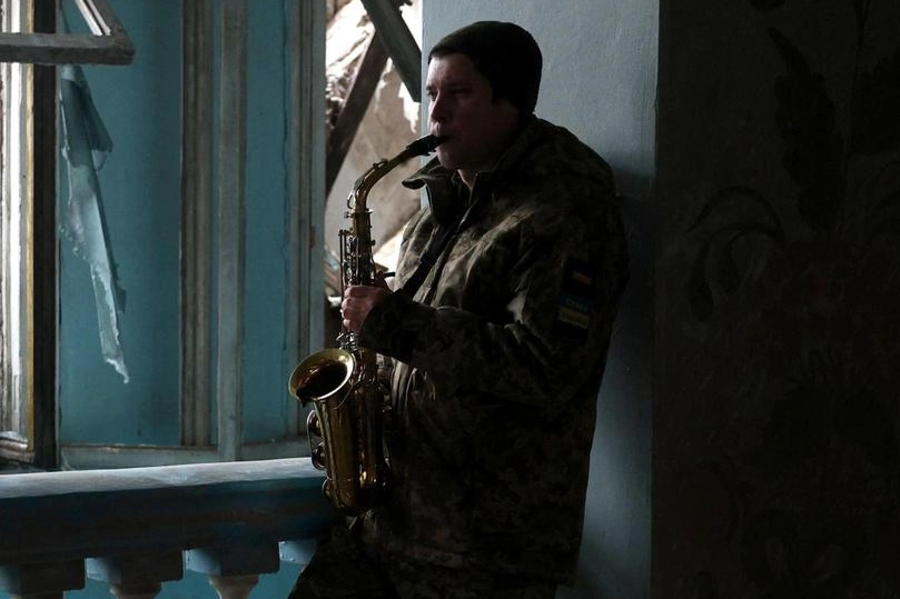 Soldato ucraino suona il sassofono tra le macerie