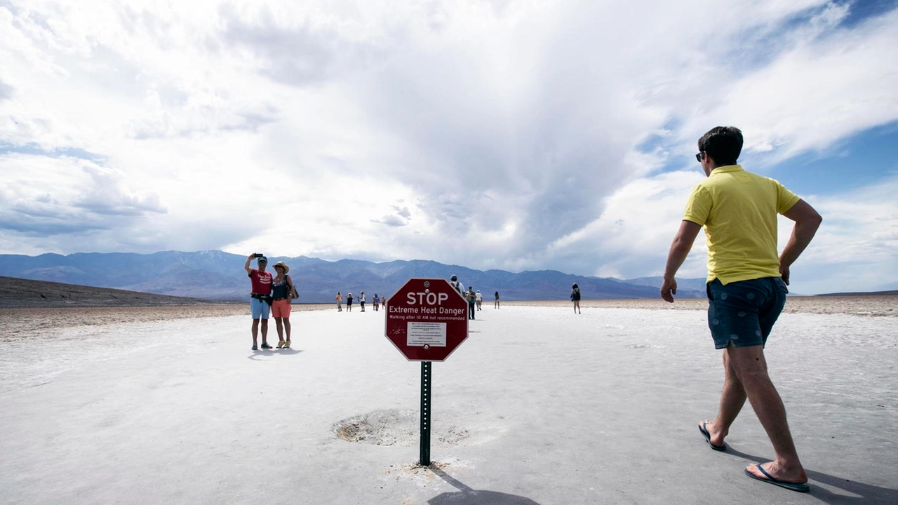 Un turista a Furnace Creek, il cartello avverte del rischio per le alte temperature (Ansa)