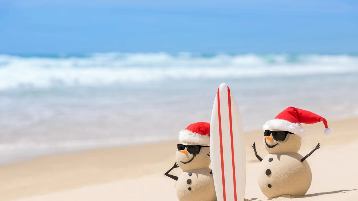 Two Sandy Christmas Snowmen with a surf board