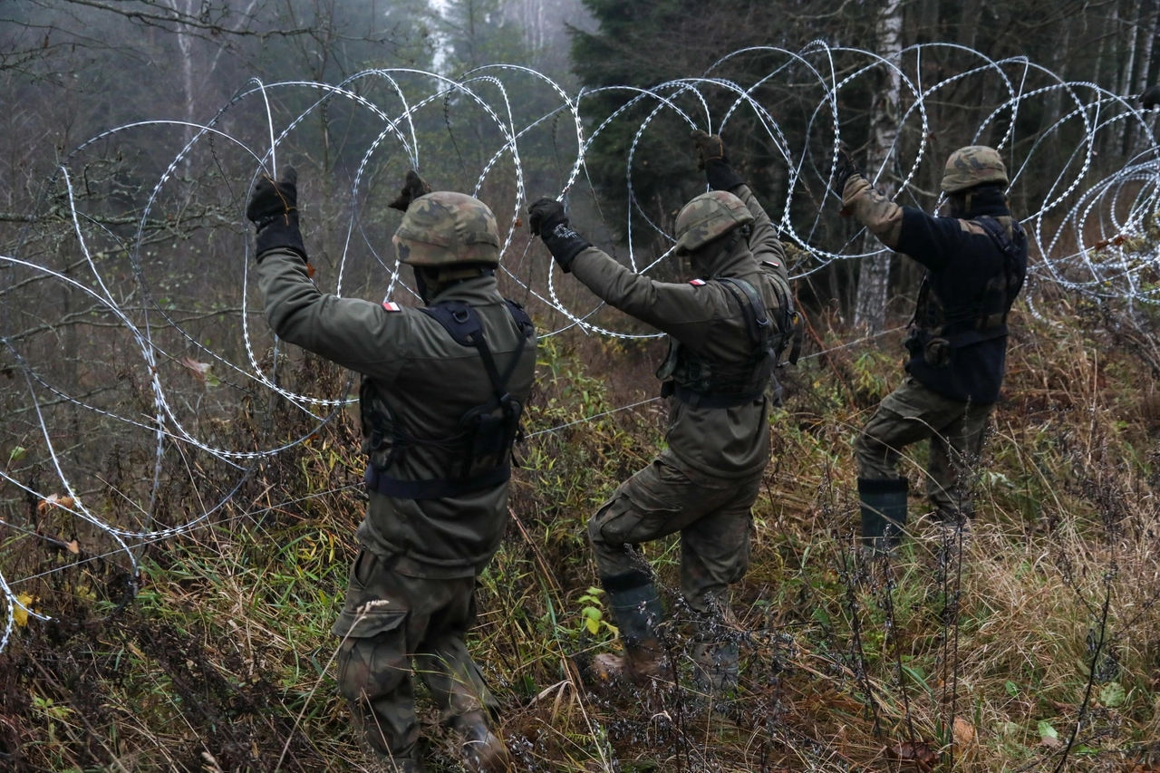 Soldati polacchi piazzano del filo spinato al confine con l'exclave di Kalingrad (Ansa)