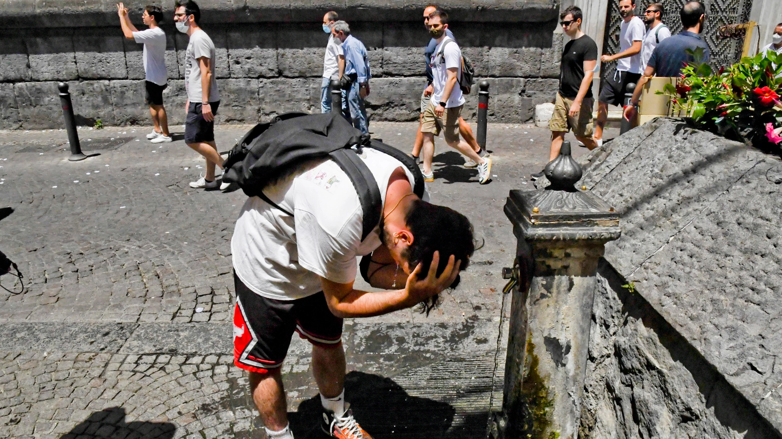 Una persona si bagna la testa per trovare sollievo dal caldo a Napoli (Ansa)