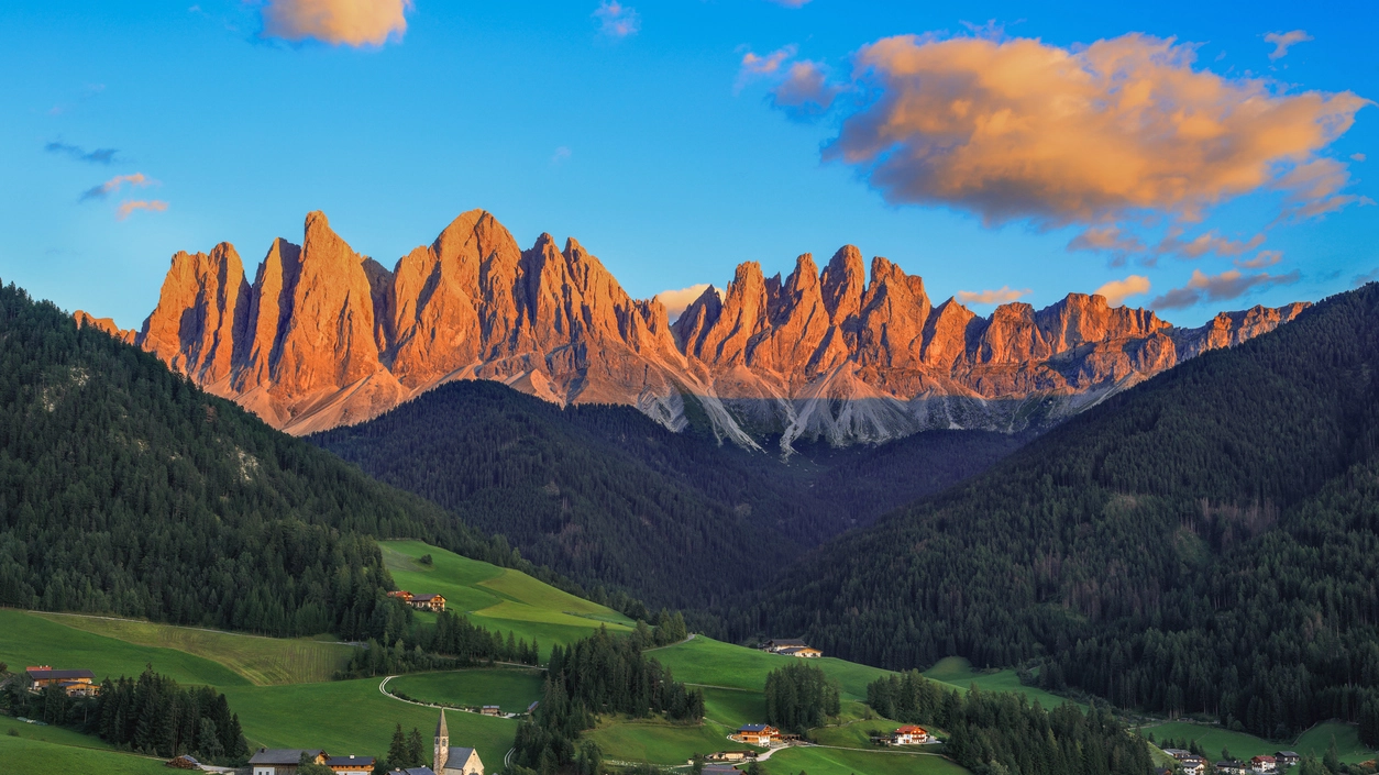 Mentre nella valle si sta facendo buio, le vette e le pareti rocciose cambiano colore al tramonto. Uno spettacolo caratteristico dei cosiddetti ‘Monti Pallidi’