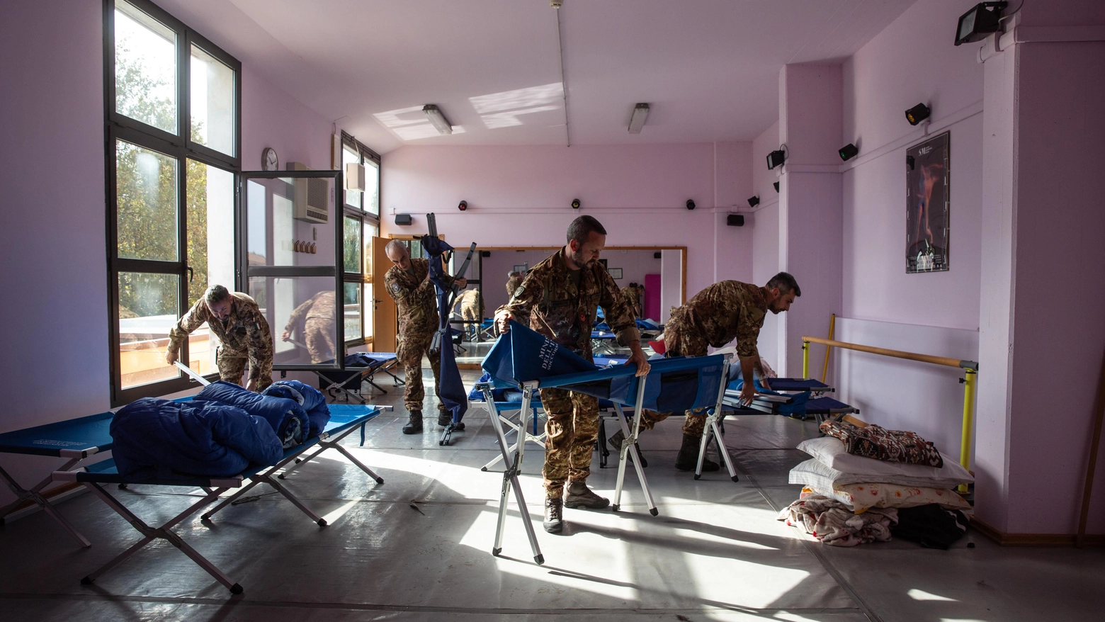 L'esercito e la Protezione Civile disallestiscono le brande al palazzetto per spostarsi alla bocciofila di Budrio (foto Ansa)