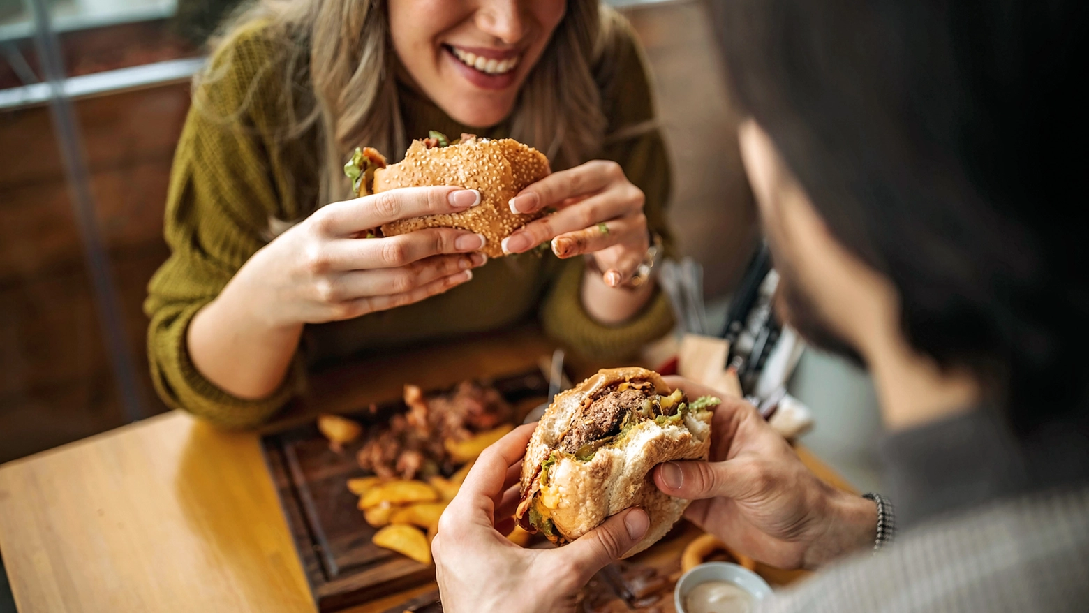 Giovani mangiano un hamburger (foto generica)