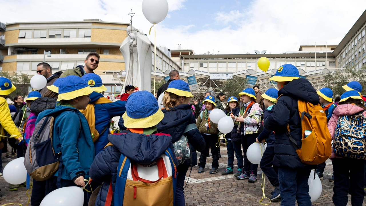 Un gruppo di bambini davanti alla statua di Giovanni Paolo II dell'ospedale Gemelli (Ansa)