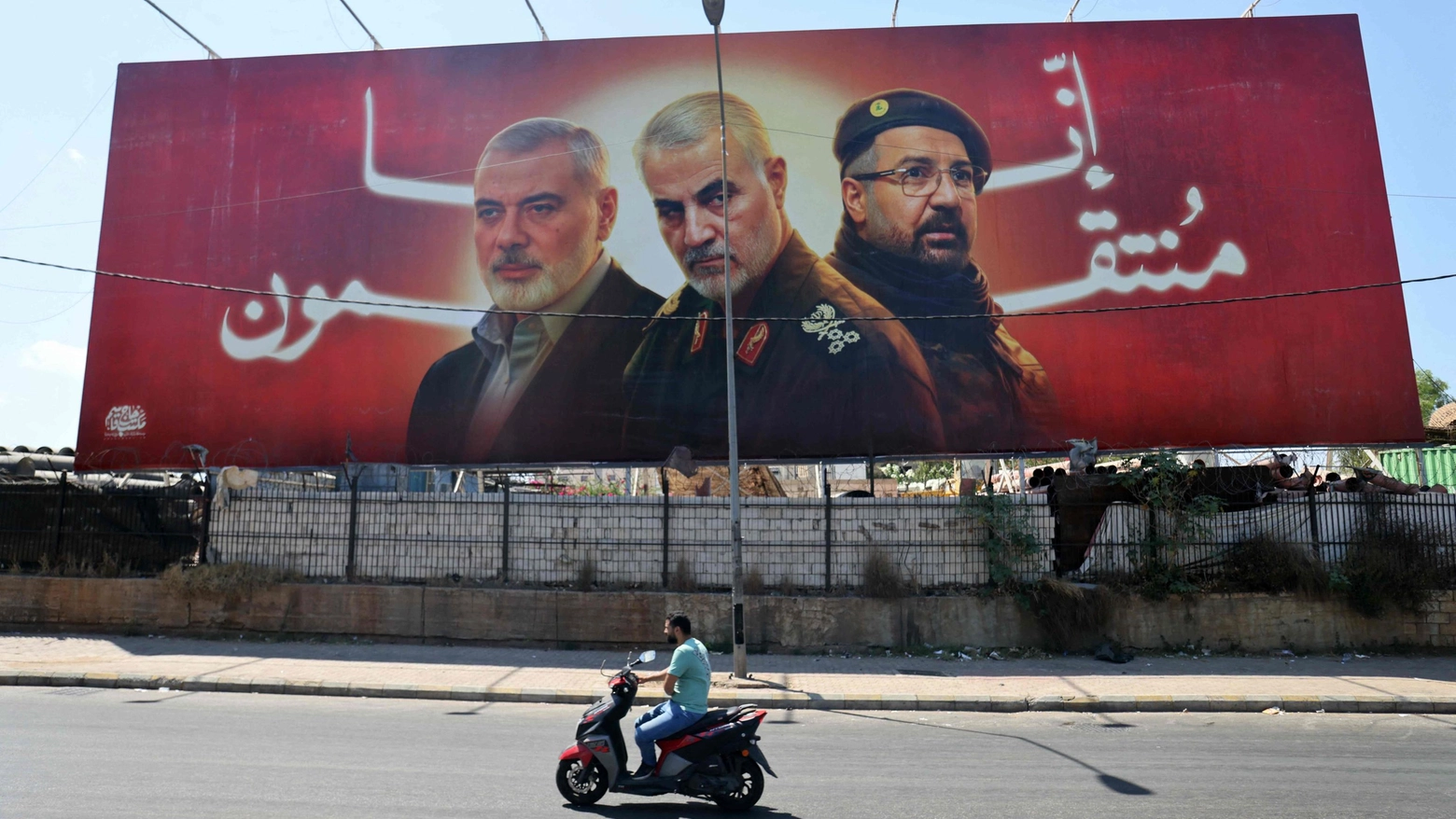 Un cartellone con il ritratto di Ismail Haniyeh, Qasem Soleimani e Fuad Shukr in una strada vicino all'aeroporto di Beirut (Ansa)