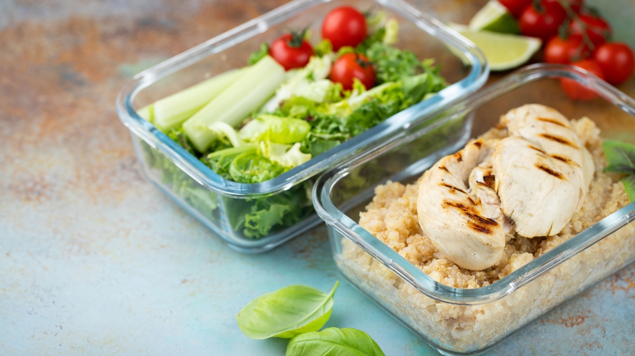 Healthy meal prep containers with quinoa, chicken breast and green salad overhead shot with copy space