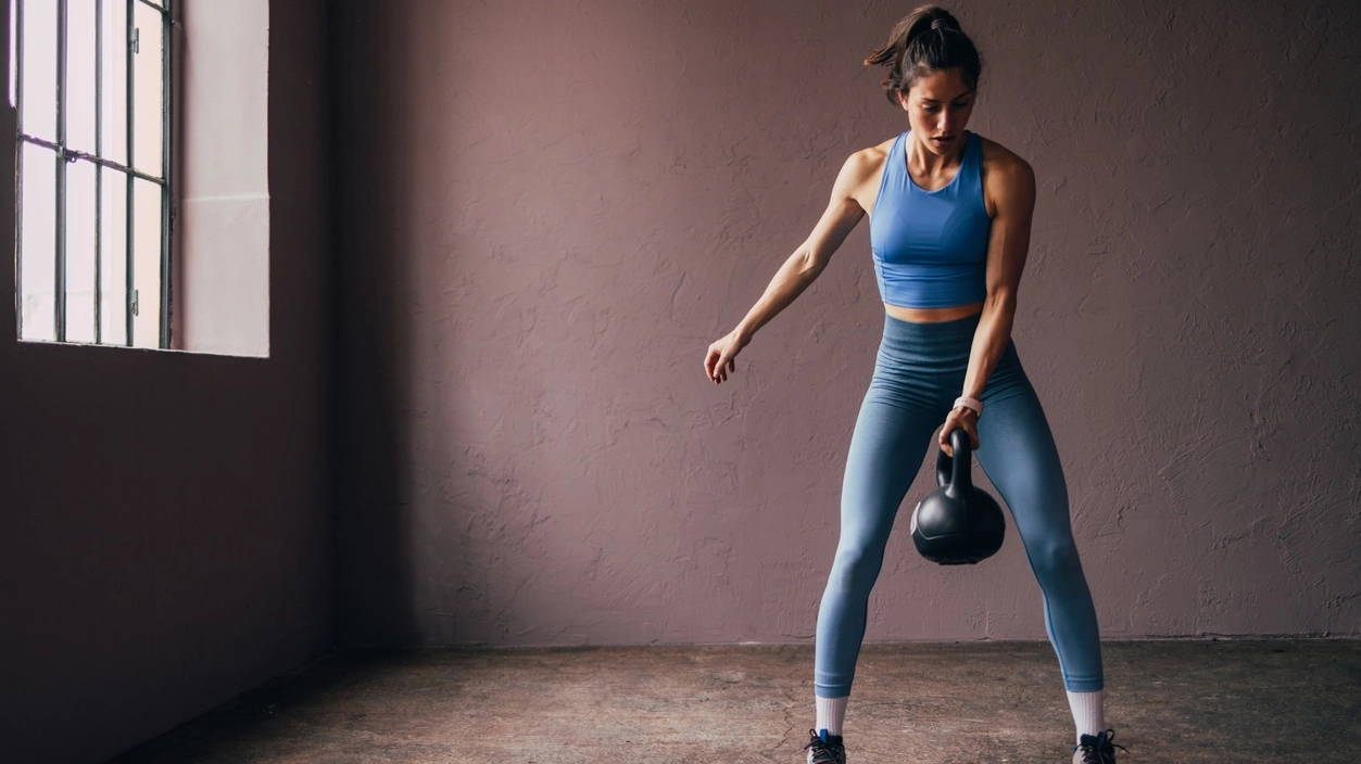 Focused Woman Exercising with Kettlebell in a Gym Setting