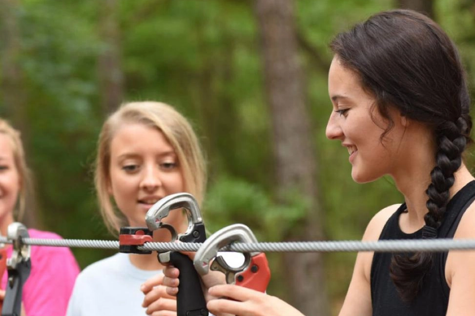 Una istruttrice del Jungle adventure park insegna come usare i moschettoni per la propria sicurezza in quota