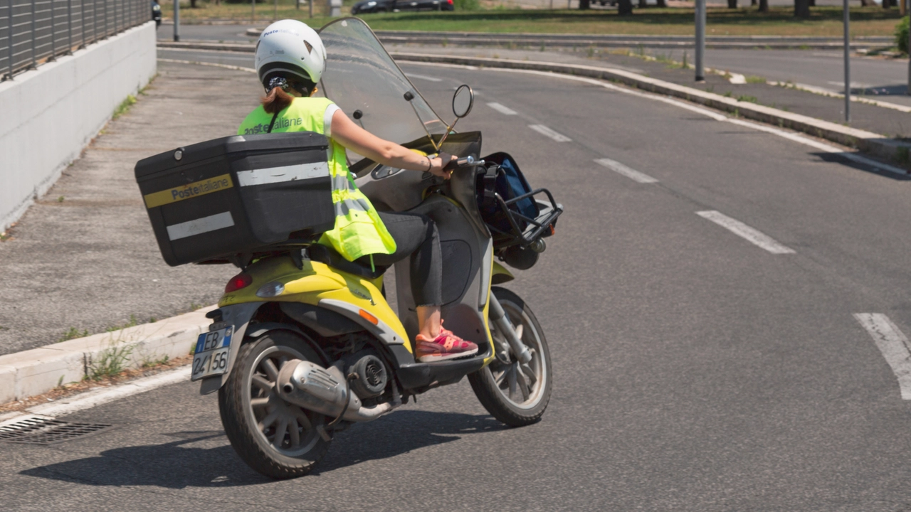 Rome, Italy - July 1, 2020: a postman on a motorcycle delivers mail in a suburban area of Rome, Italy.