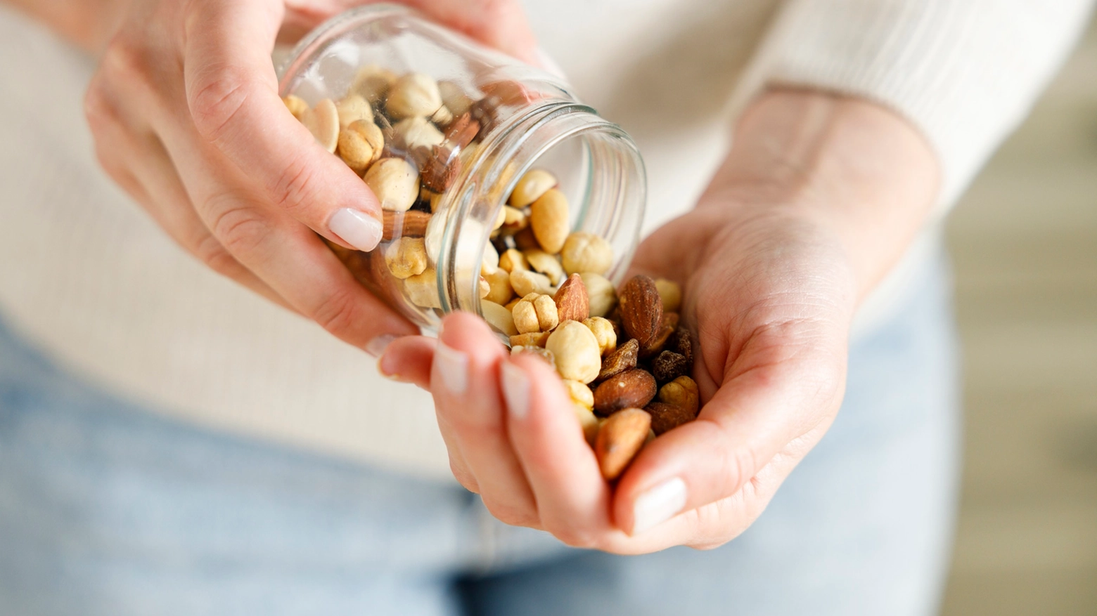 Nuts spilling from jar in woman's hand