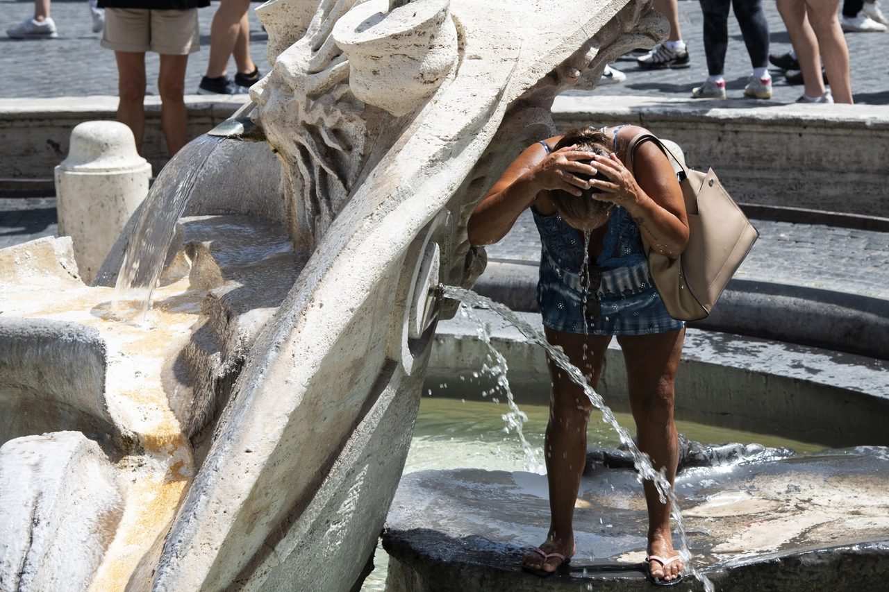 Caldo, una donna si rinfresca nella fontana (Italy Photo Press)