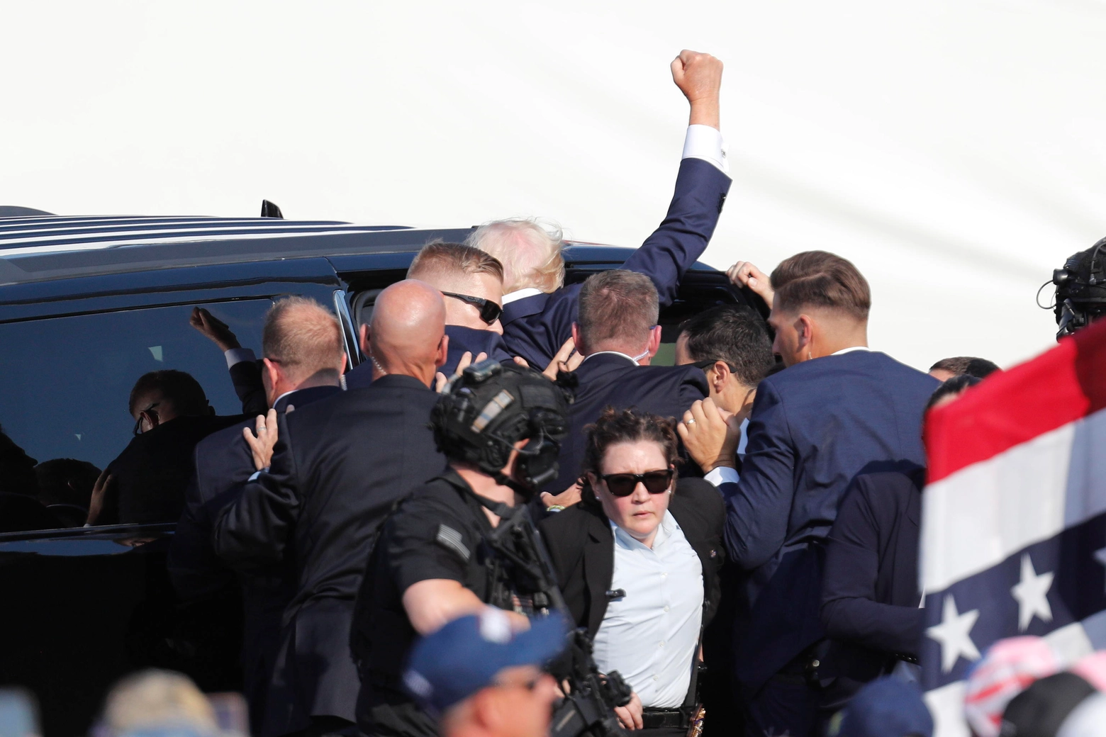 Il presidente Trump, col pugno alzato subito dopo essere stato ferito, viene caricato in un'auto blindata dai servizi di sicurezza