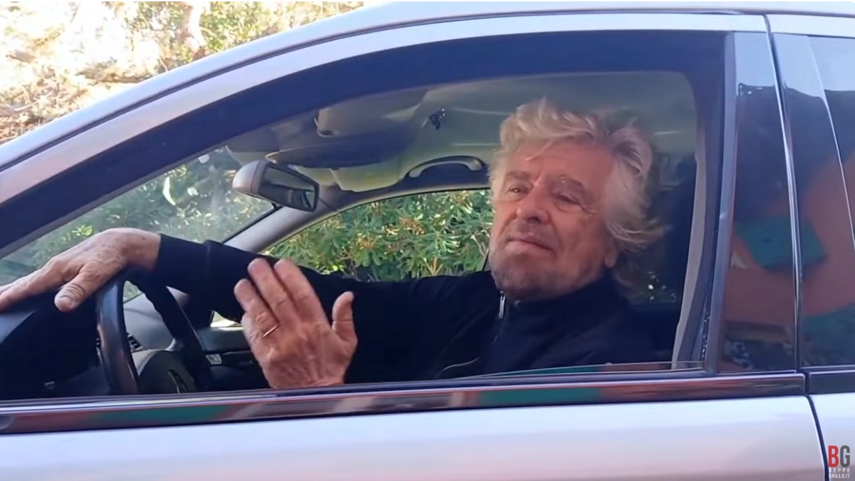 Beppe Grillo alla guida di un carro funebre parla del M5s