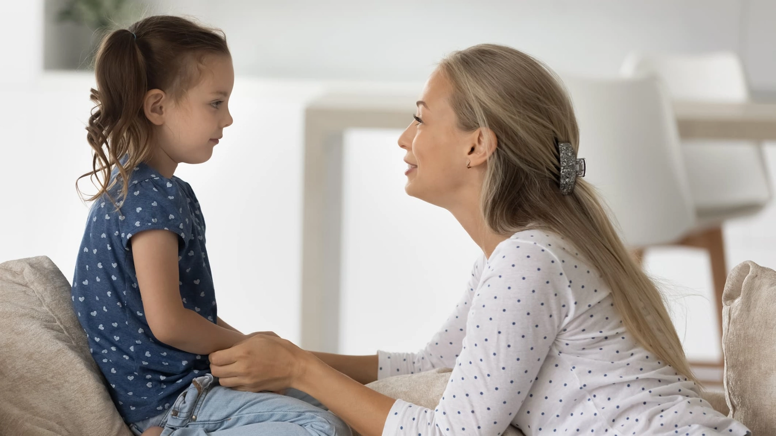 Smiling young woman involved in sincere conversation with child daughter.