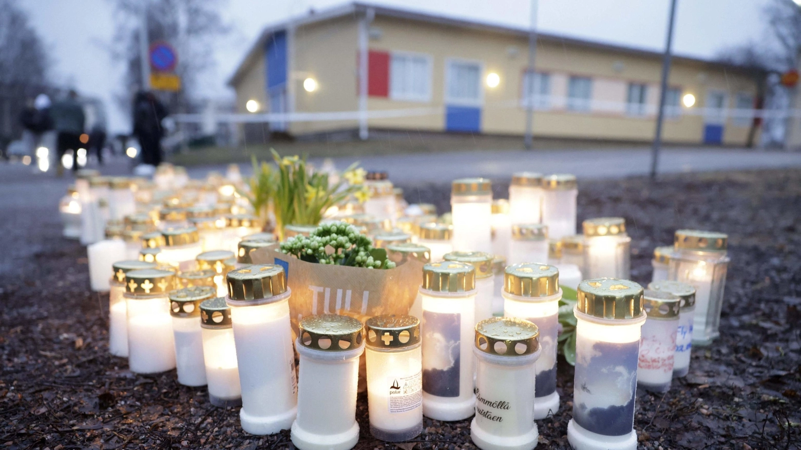 Fiori e candele lasciati fuori dalla scuola teatro della sparatoria (Ansa)