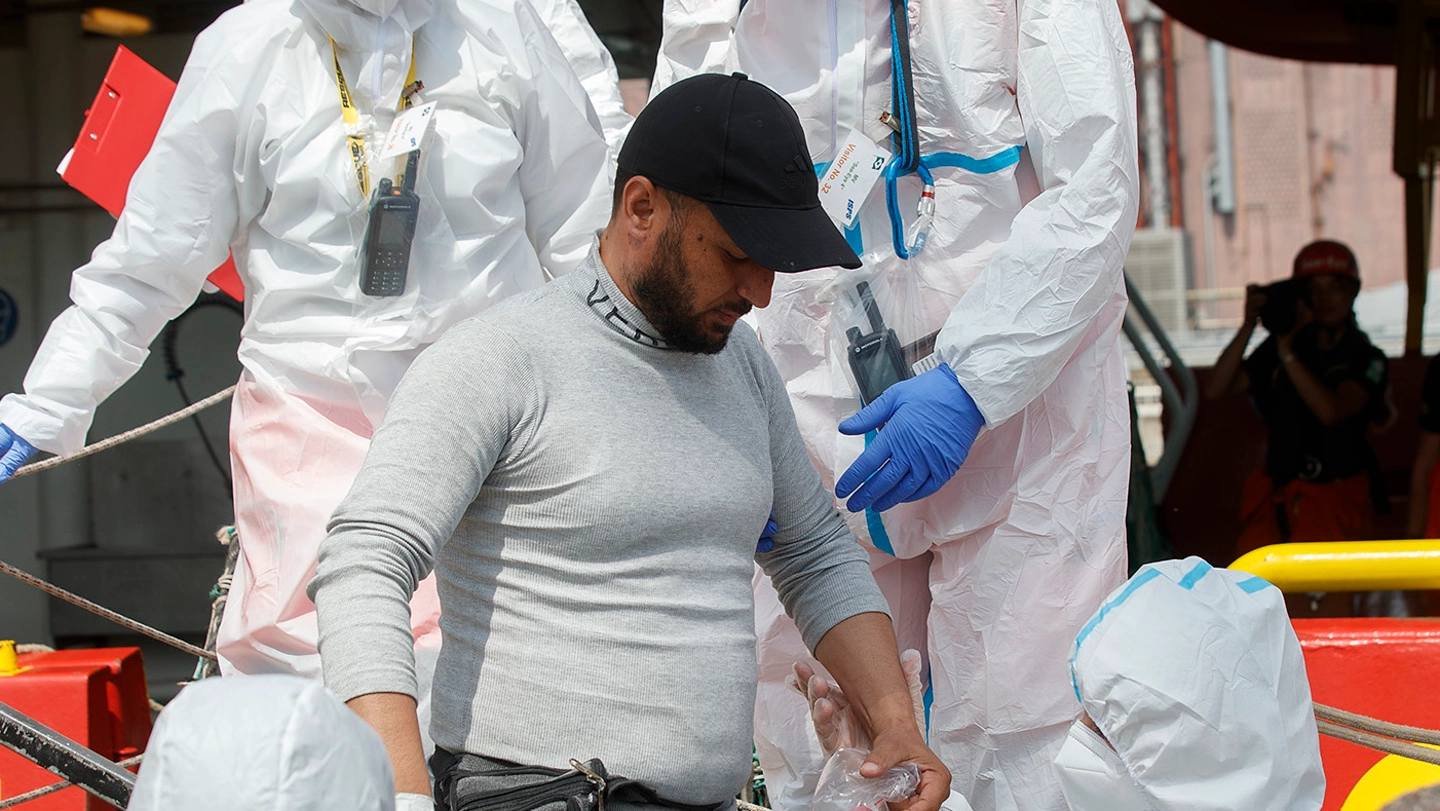 Gli operatori sanitari e i volontari aiutano un migrante arrivato sulle coste italiane a sbarcare a terra