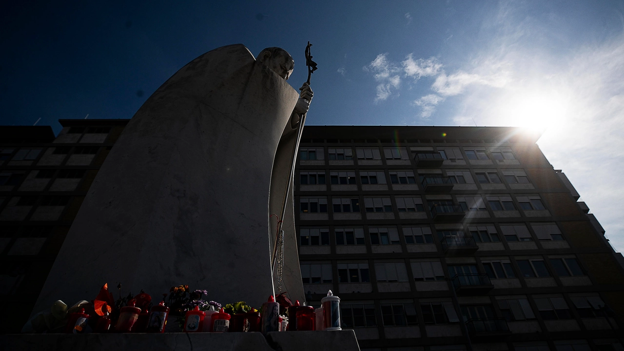 Candele sotto la statua di Giovanni Paolo II all'ingresso del Policlinico Gemelli, dove è ricoverato Papa Francesco