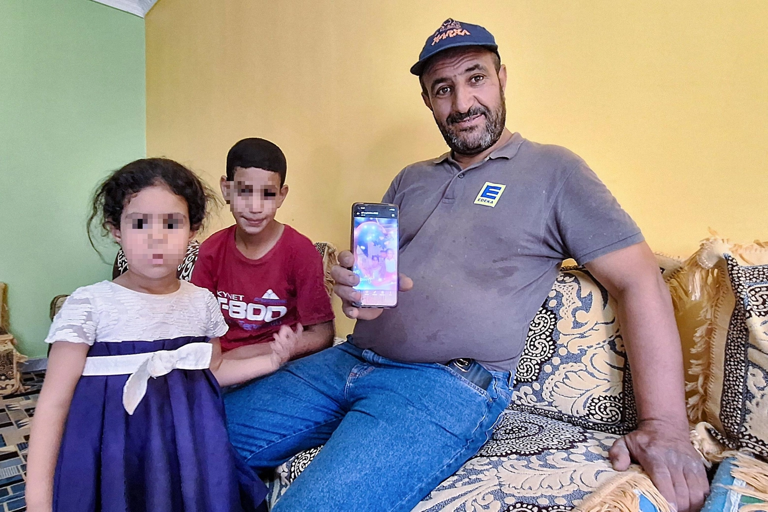 Omar Khelif mostra una foto di sua figlia Imane da bambina. Accanto a lui altri due figli piccoli