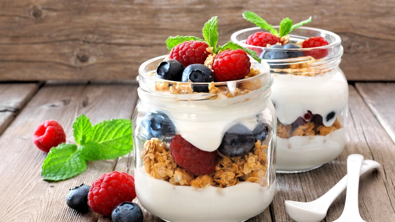 Blueberry, raspberry parfaits in mason jars, still life against wood