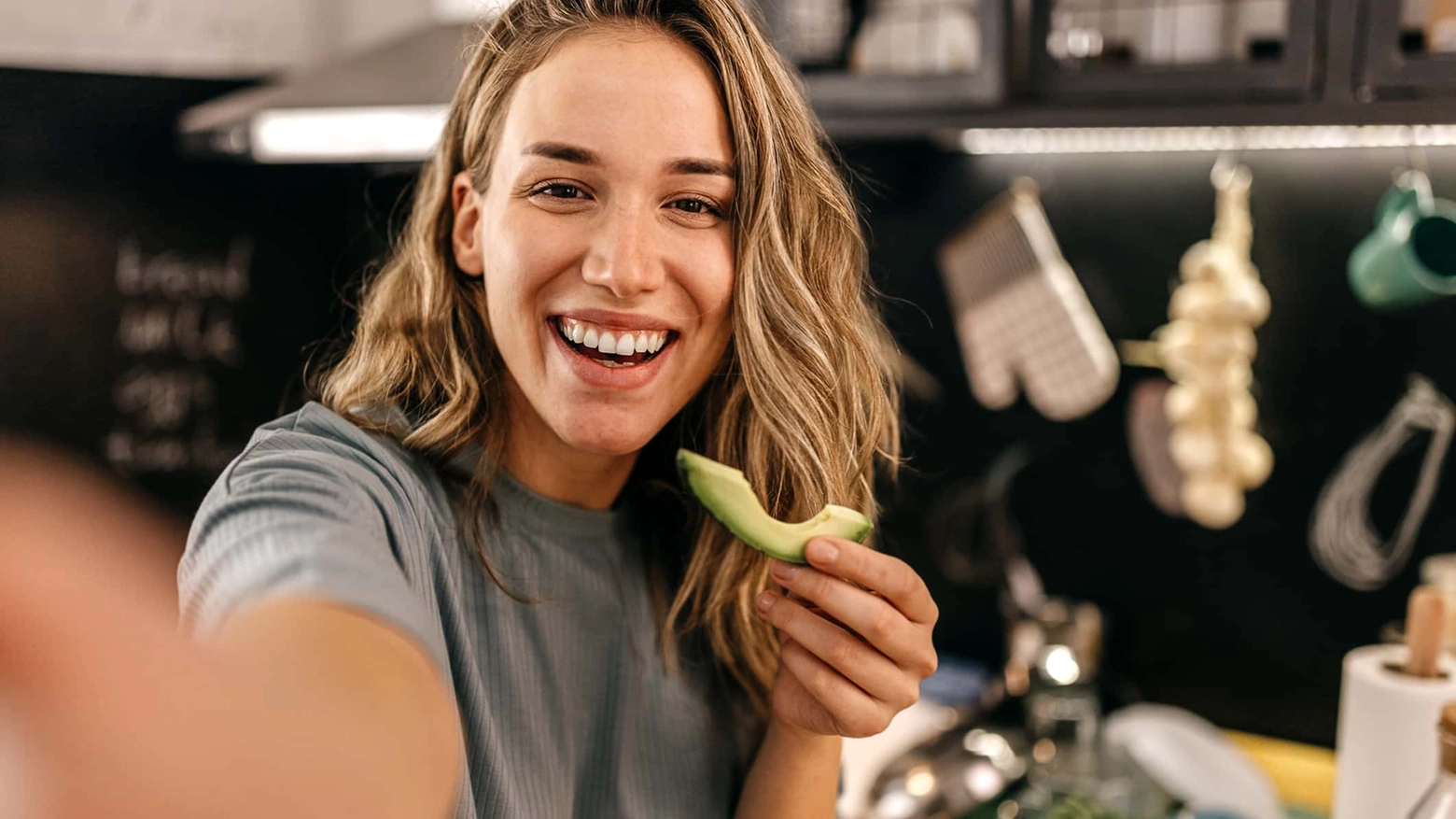 Woman eating avocado and taking selfie