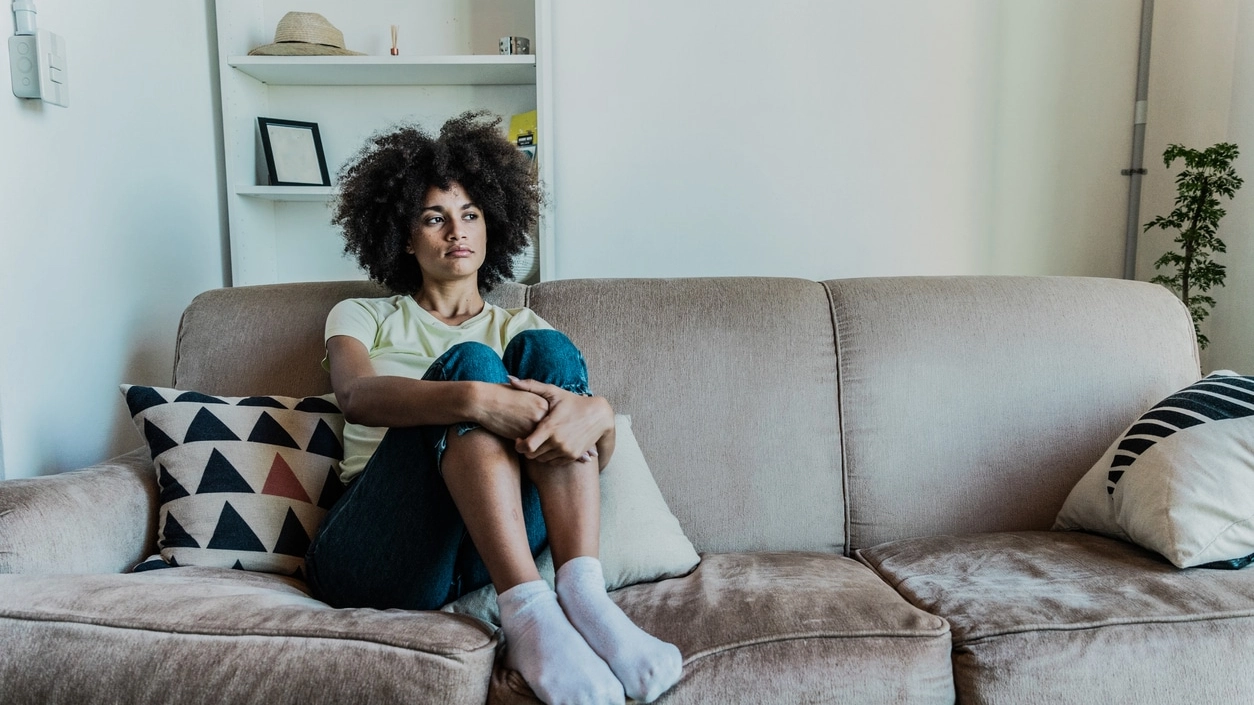 Sad young woman looking away in the living room at home